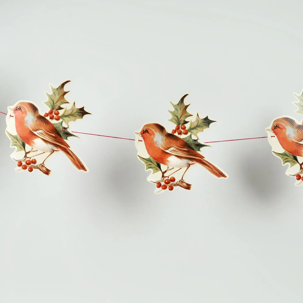 Decorative string with birds and holly leaves on a light gray background